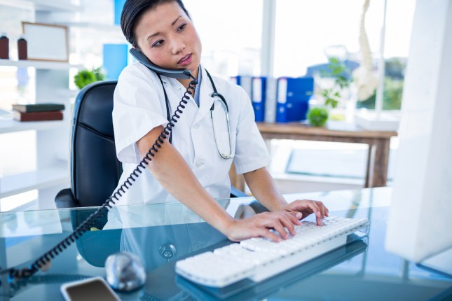 Doctor having phone call and using her computer in medical offic